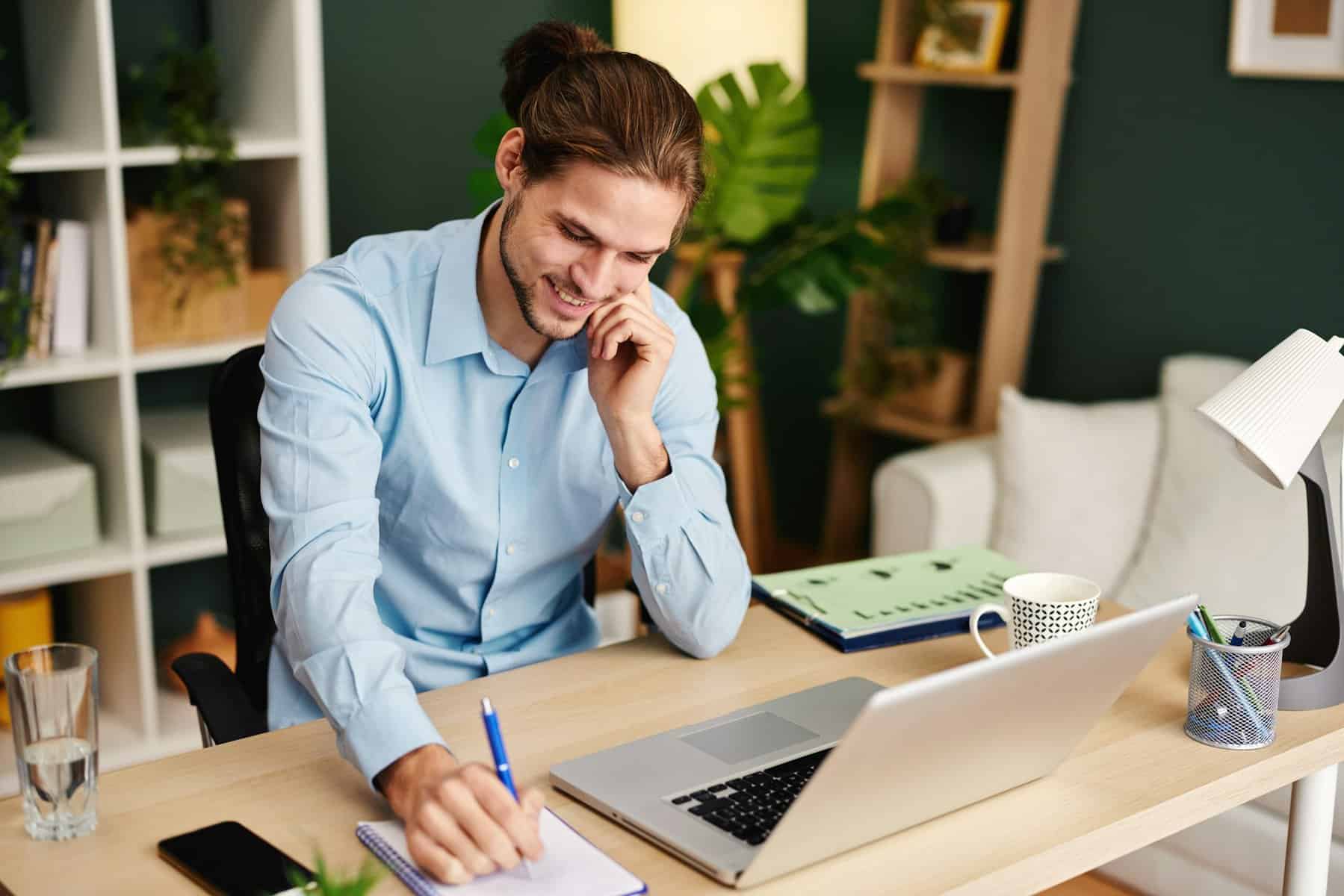 Young business man working at home with laptop and papers on desk